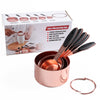 Set of copper measuring cups with black handles and a measuring cup set box in the background.