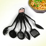 Set of black kitchen utensils with a bowl of spaghetti in the background