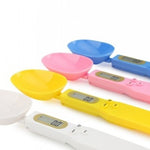 Colorful kitchen measuring tools including spoons, a scale, and digital rulers on a white background.