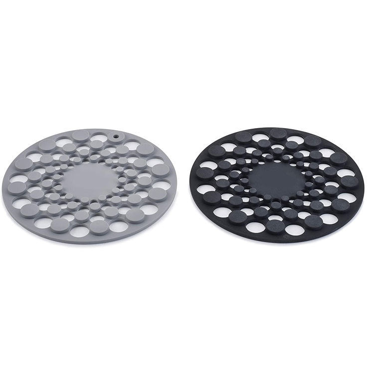 Two round silicone trivets, one gray and one black, on a white background.