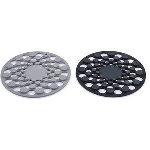 Two round silicone trivets, one gray and one black, on a white background.