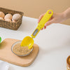 Yellow digital kitchen scoop being used to measure grains on a white surface with a basket of eggs in the background.
