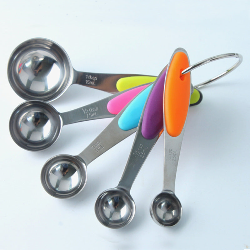Set of metal measuring spoons with colorful silicone handles on a white background