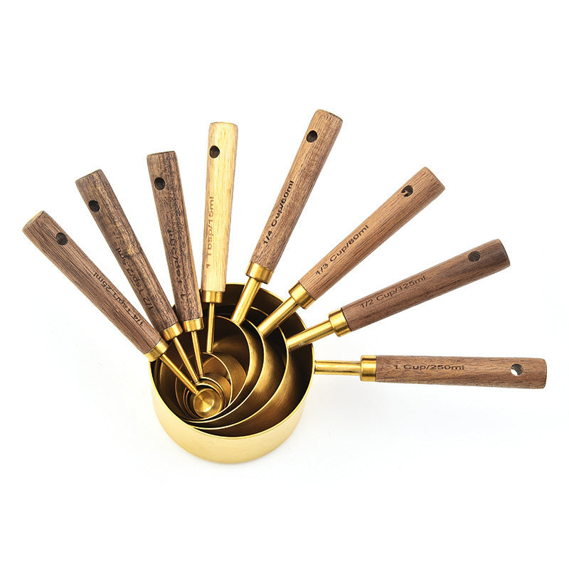 Set of gold measuring cups with wooden handles on a white background