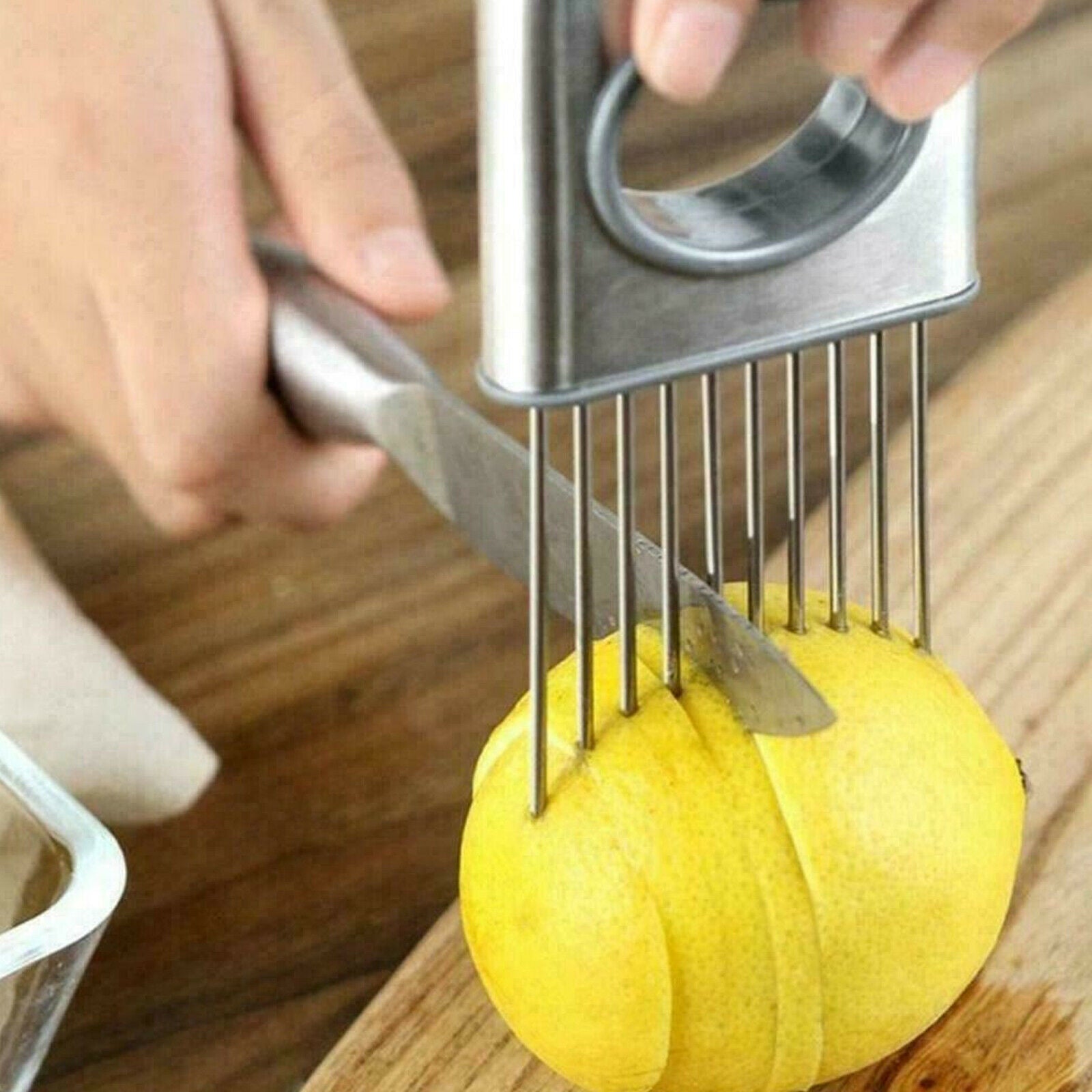 Lemon being sliced with a stainless steel lemon squeezer on a wooden surface.
